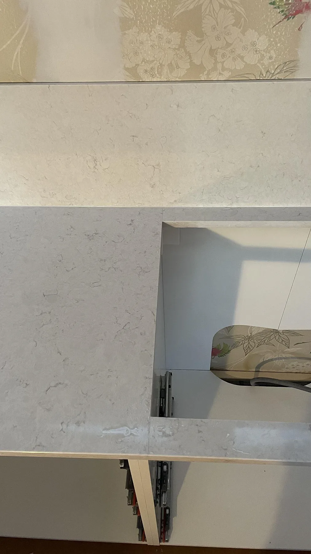 Polerad Silestone Snowy Ibiza bänkskiva med utsågad hällöppning och stänkskydd ovanför köksstommar i Fjällbacka.