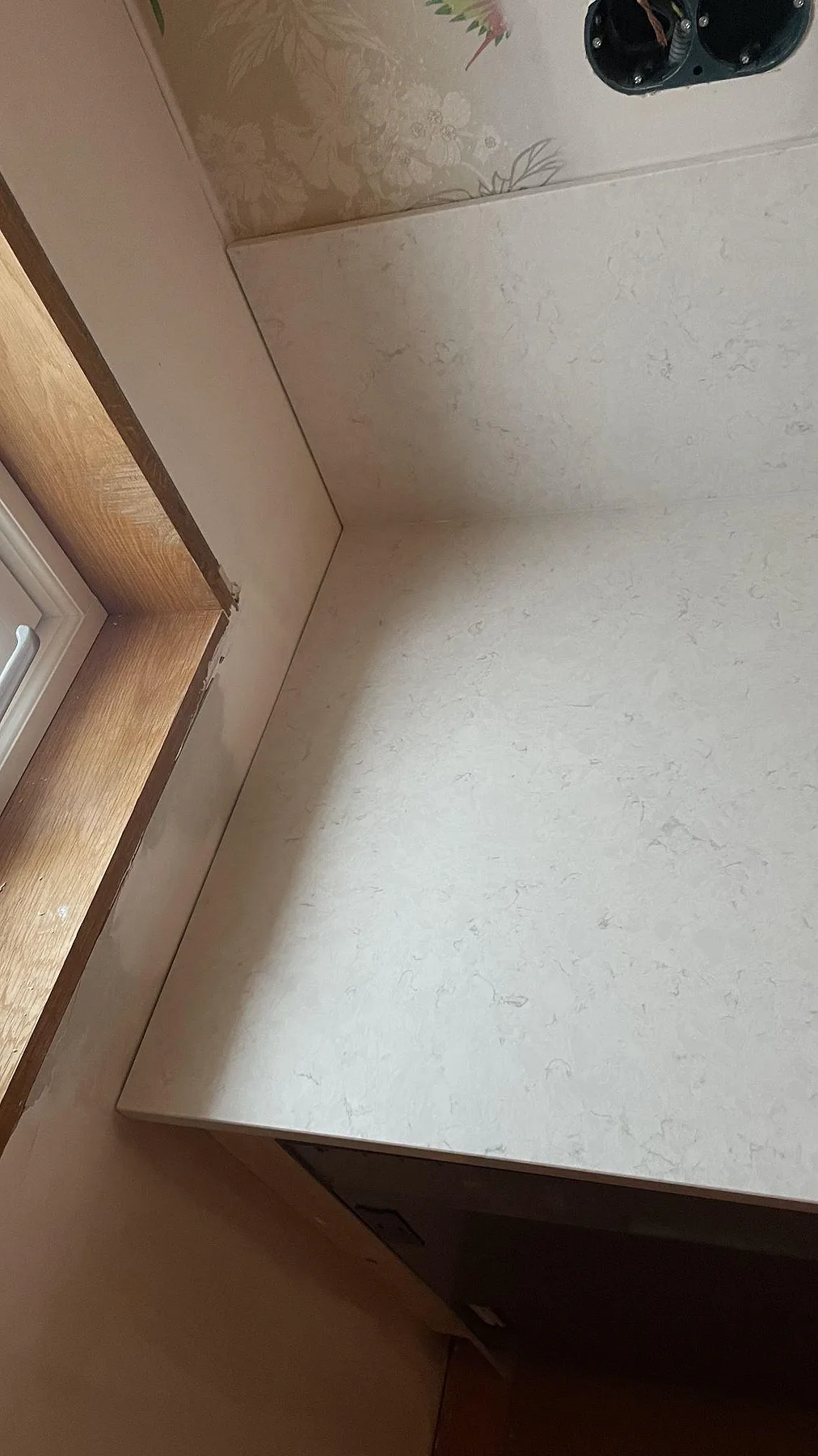 Sidovy av polerad Silestone Snowy Ibiza bänkskiva mot fönster och vägg med stänkskydd i Fjällbacka.