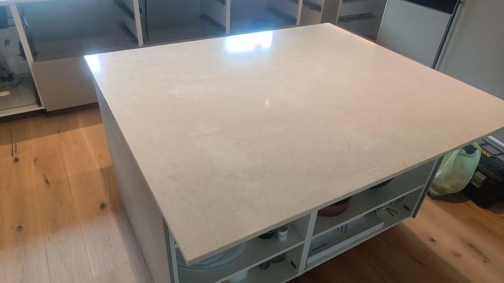 Stor köksö i polerad Silestone Snowy Ibiza, vit kvartskomposit, med tunn 20 mm kant i kök under montering i Fjärås.