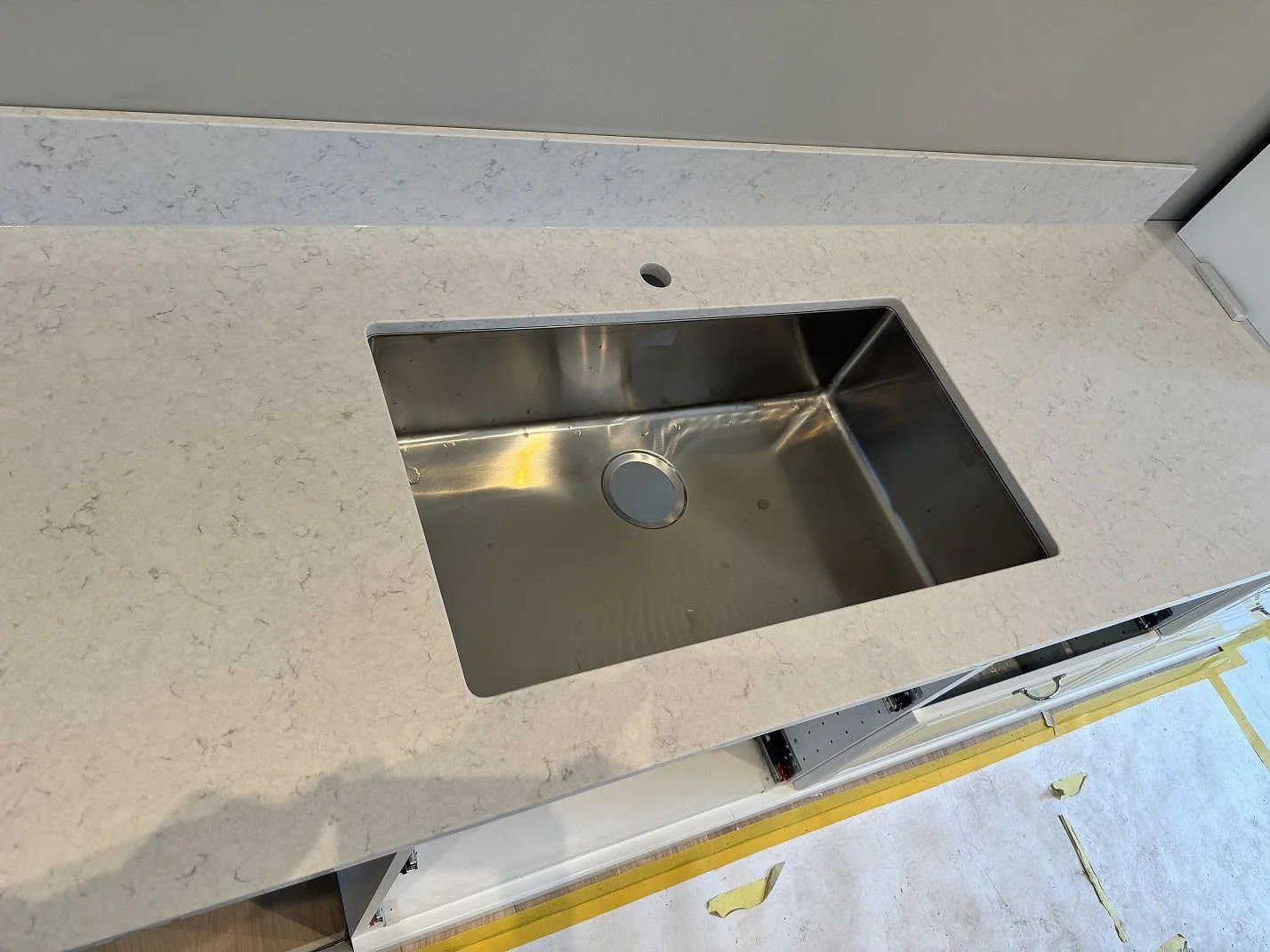 Närbild på underlimmad rostfri diskho i polerad Silestone Snowy Ibiza med kranhål och ljus ådring i Frillesås.