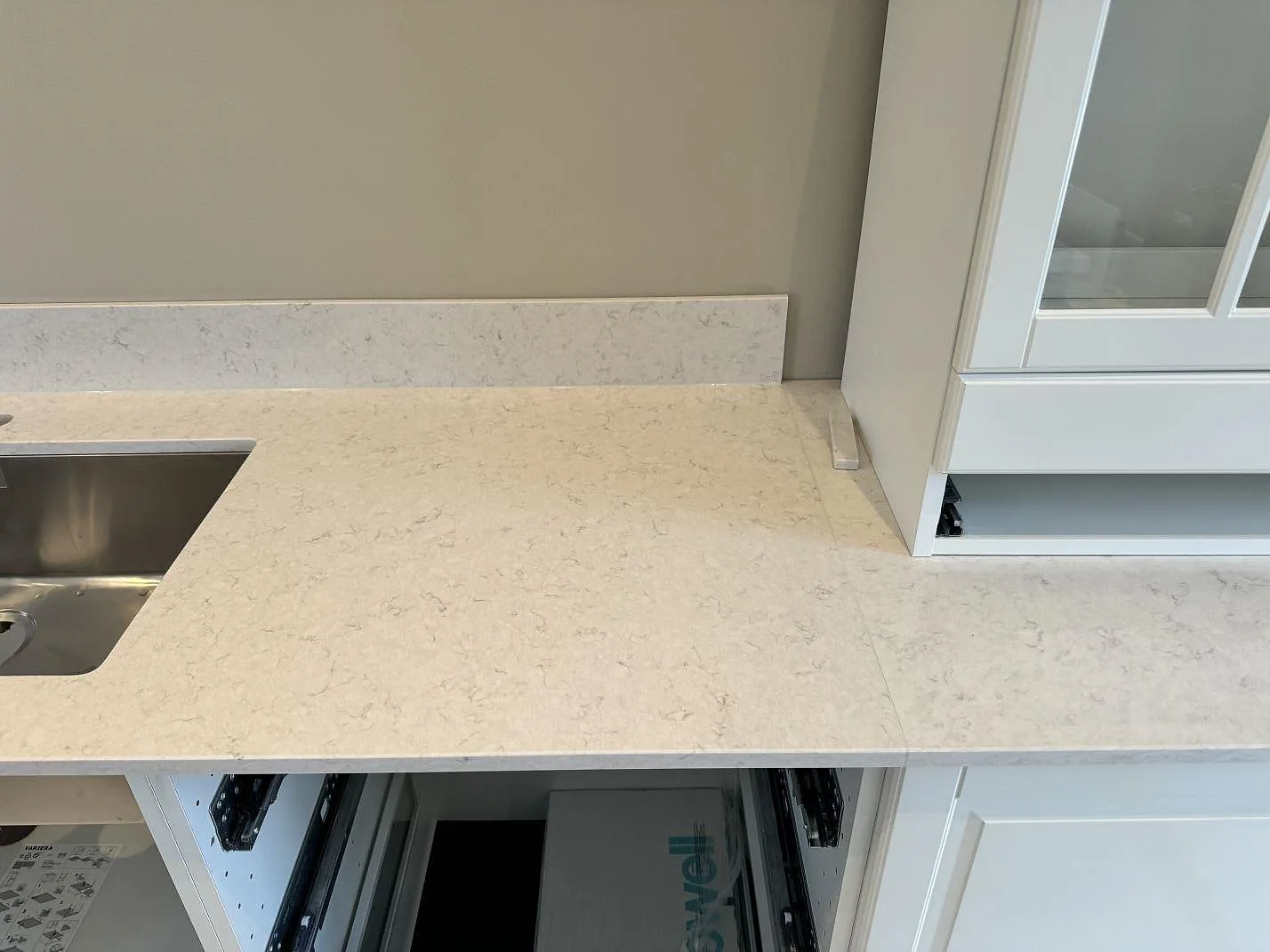 Polerad Silestone Snowy Ibiza som köksbänkskiva intill vit shakerinredning, med synlig ljus ådring och stänkkant i Frillesås.