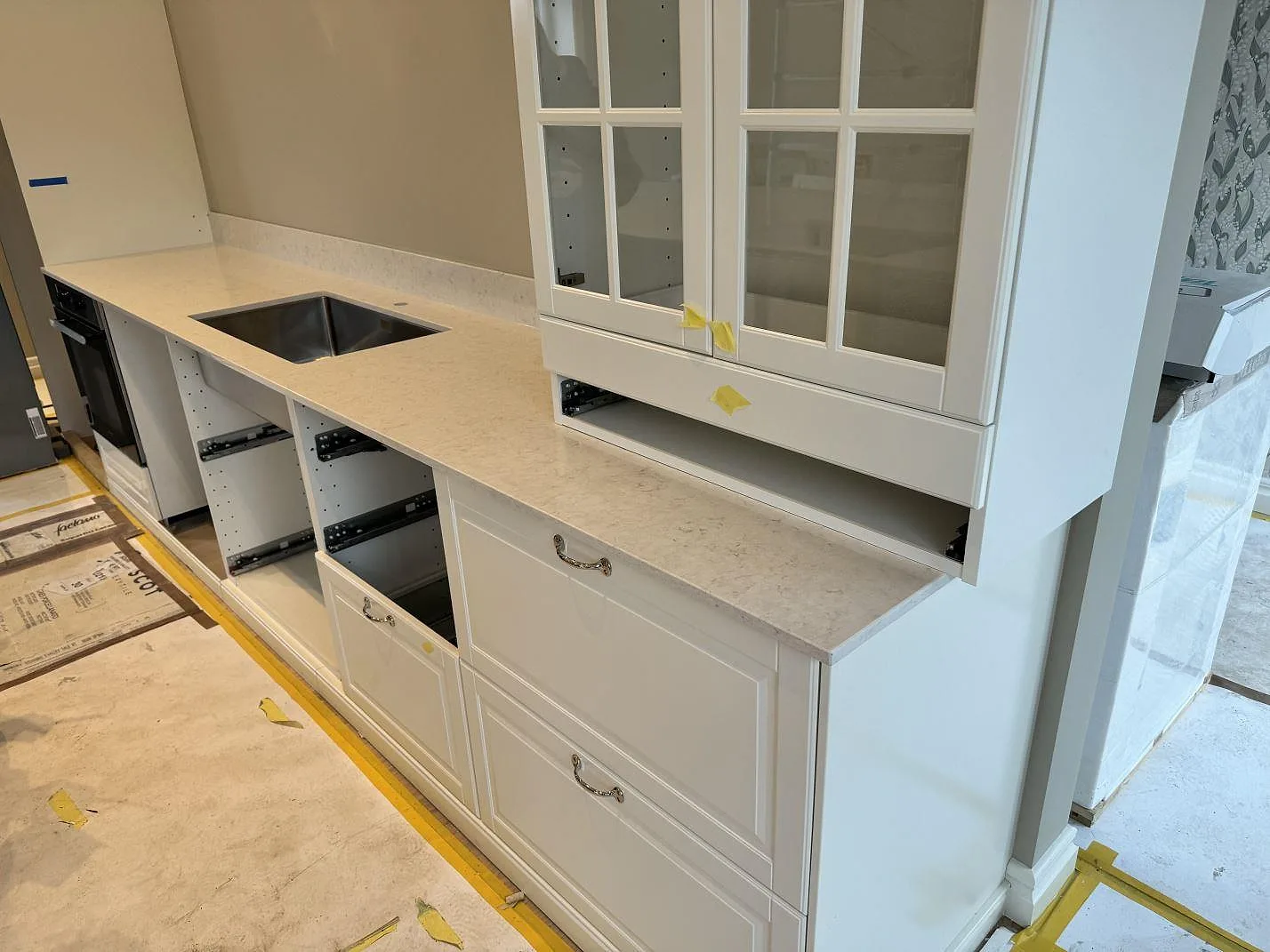 Köksbänkskiva i polerad Silestone Snowy Ibiza med underlimmad rostfri diskho, stänkkant och glasfrontade överskåp i Frillesås.