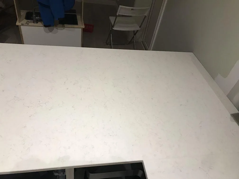 Lång polerad köksbänkskiva i Silestone Snowy Ibiza med mjuk grå ådring under montering i ett kök i Furuby.
