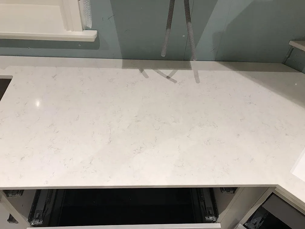 Köksbänkskiva i vit Silestone Snowy Ibiza mot målad vägg med synlig eldragning under montering i ett kök i Furuby.