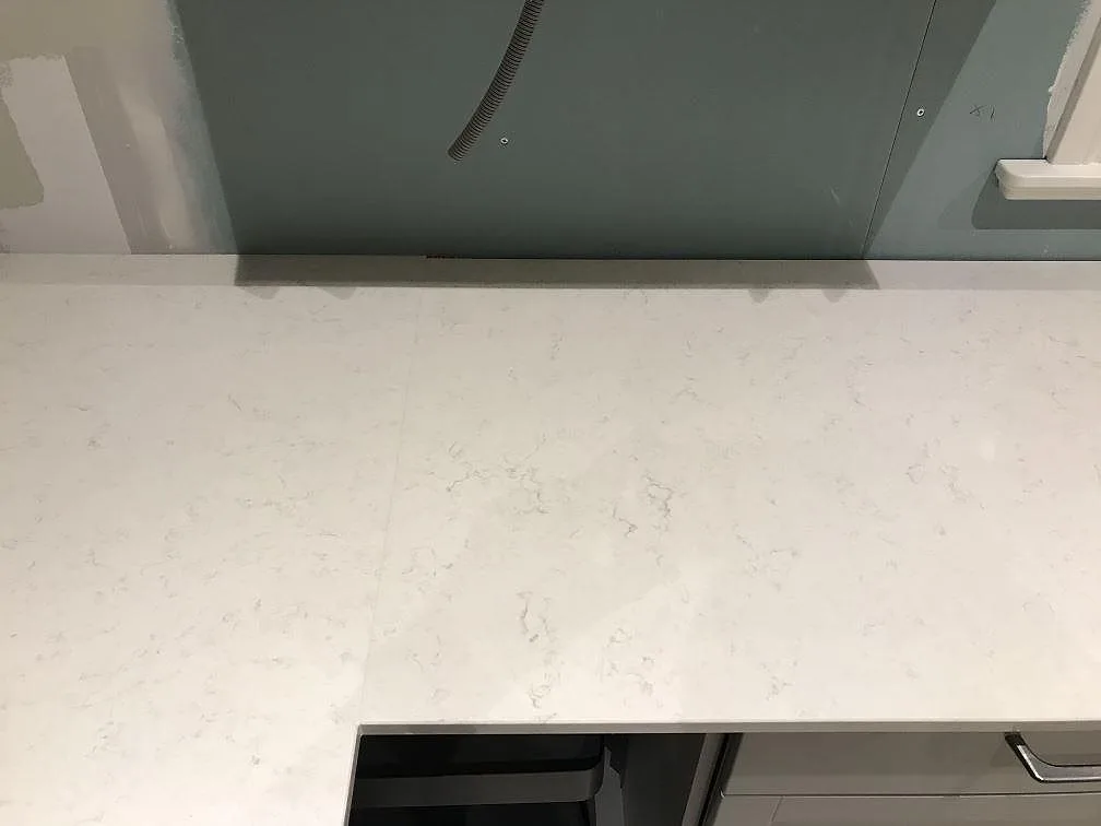 Köksbänkskiva i polerad Silestone Snowy Ibiza mot bar gipsvägg under montering i ett kök i Furuby.