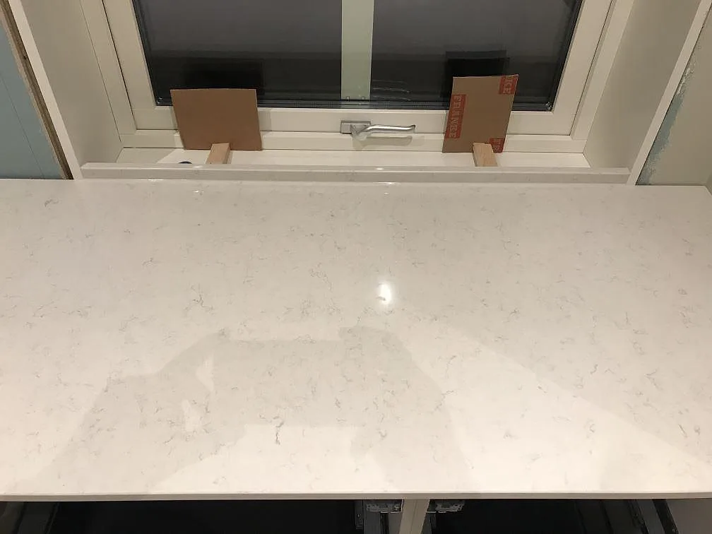 Köksbänkskiva och fönsterbänk i Silestone Snowy Ibiza under fönster i ett kök i Furuby, polerad vit kvartskomposit.