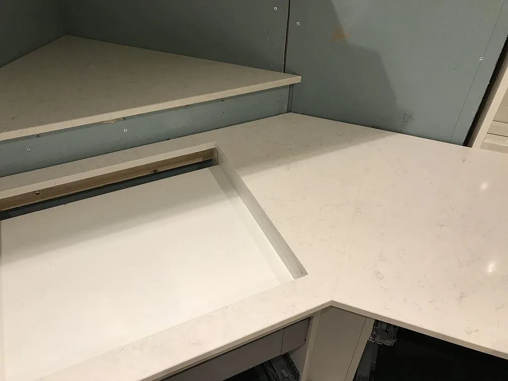 Vinkelbänk i Silestone Snowy Ibiza med urtag för diskho i ett kök under montering i Furuby.