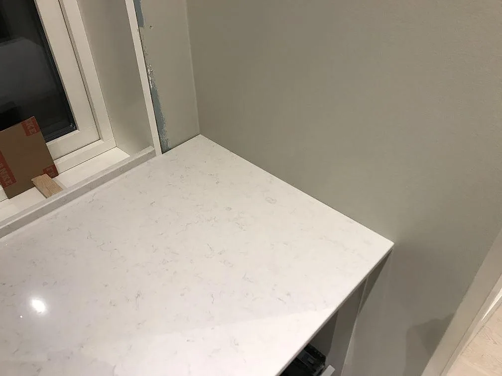 Polerad köksbänkskiva i Silestone Snowy Ibiza med ljusreflekterande kant vid fönster i ett kök i Furuby.