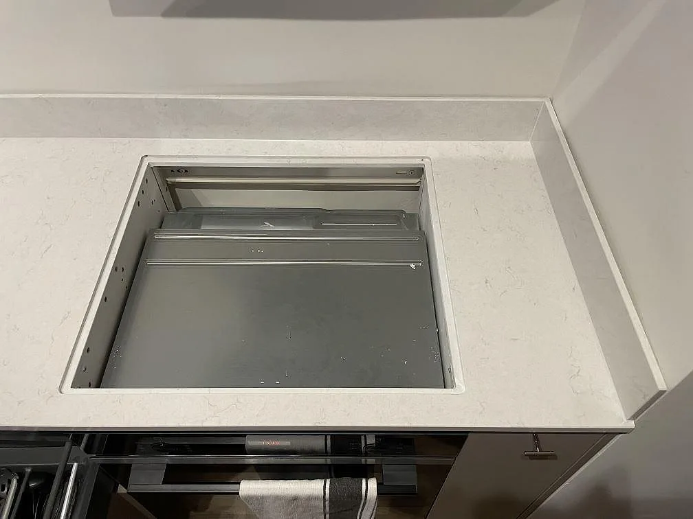 Hällzon i polerad Silestone Snowy Ibiza med uppvikt stänkkant ovanför ugnen i ett kök i Gävle.