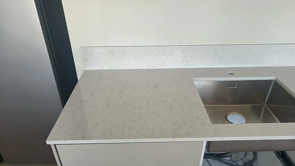 Polerad köksbänkskiva i Silestone Snowy Ibiza med underlimmad rostfri diskho och uppvikt stänkkant i ett kök i Gislaved.