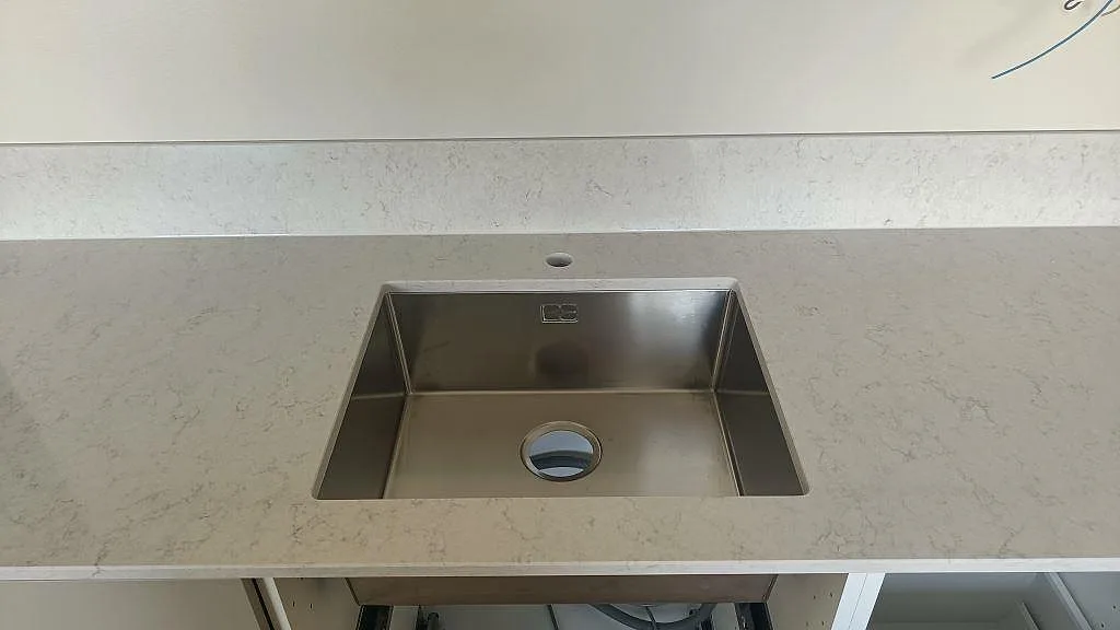 Underlimmad rostfri diskho infälld i vit Silestone Snowy Ibiza köksbänkskiva, sedd ovanifrån, i Gislaved.
