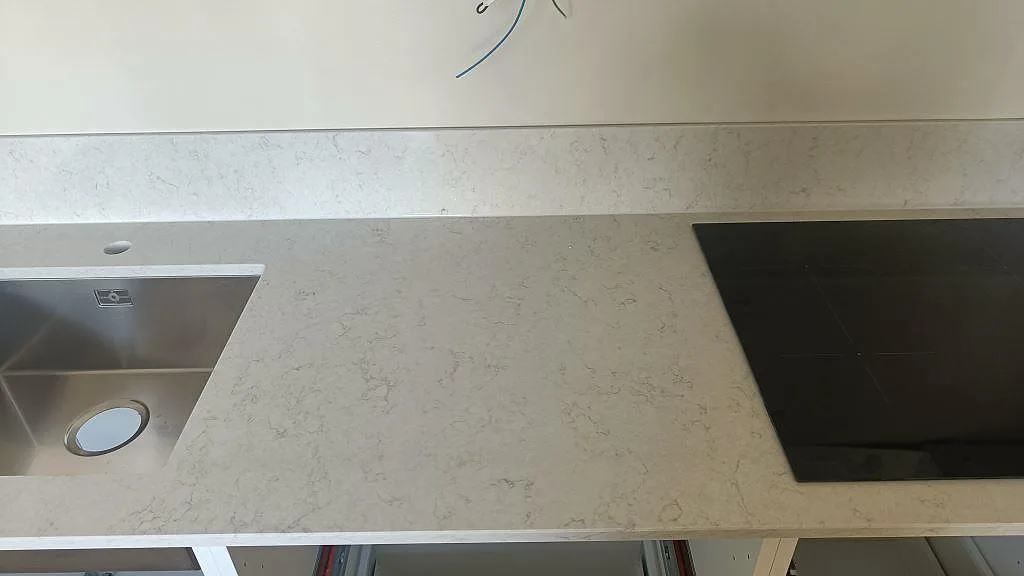 Köksbänkskiva i Silestone Snowy Ibiza med underlimmad diskho och infälld induktionshäll i samma bänk i Gislaved.
