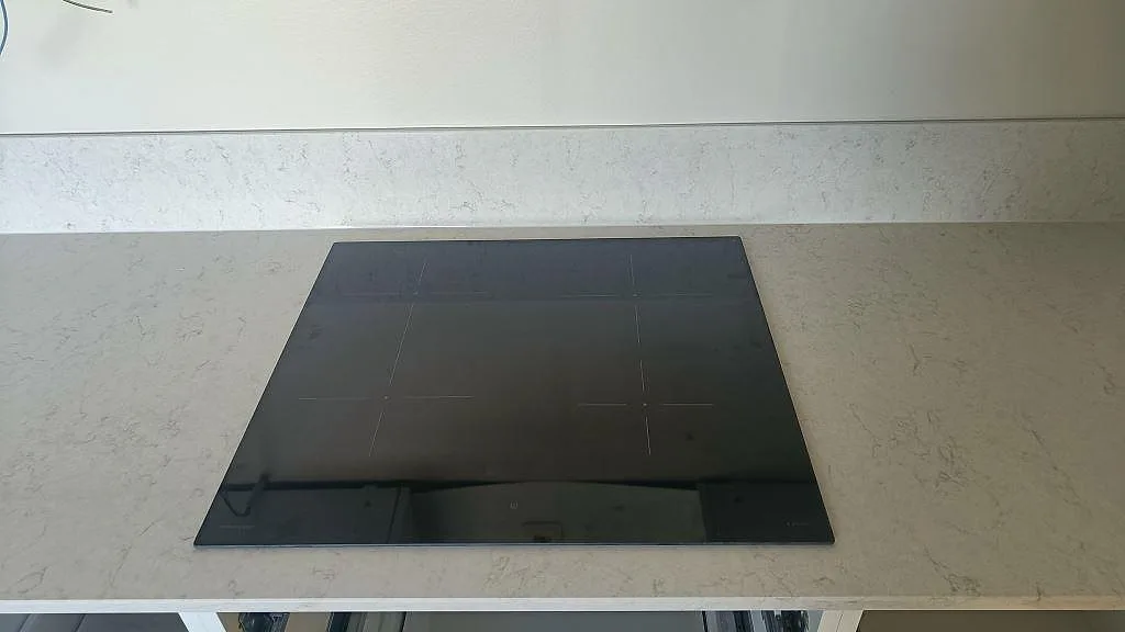 Infälld induktionshäll i polerad vit Silestone Snowy Ibiza köksbänkskiva, ovanifrån, i ett kök i Gislaved.