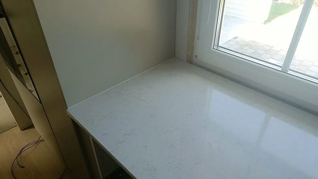Polerad Silestone Snowy Ibiza köksbänkskiva vid fönster med mjuk grå ådring i ett kök i Gislaved.