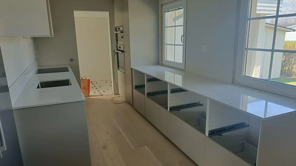 Köksbänkskiva i vit Silestone Snowy Ibiza, polerad, i ett kök under montering med induktionshäll och underlimmad diskho i Gislaved.