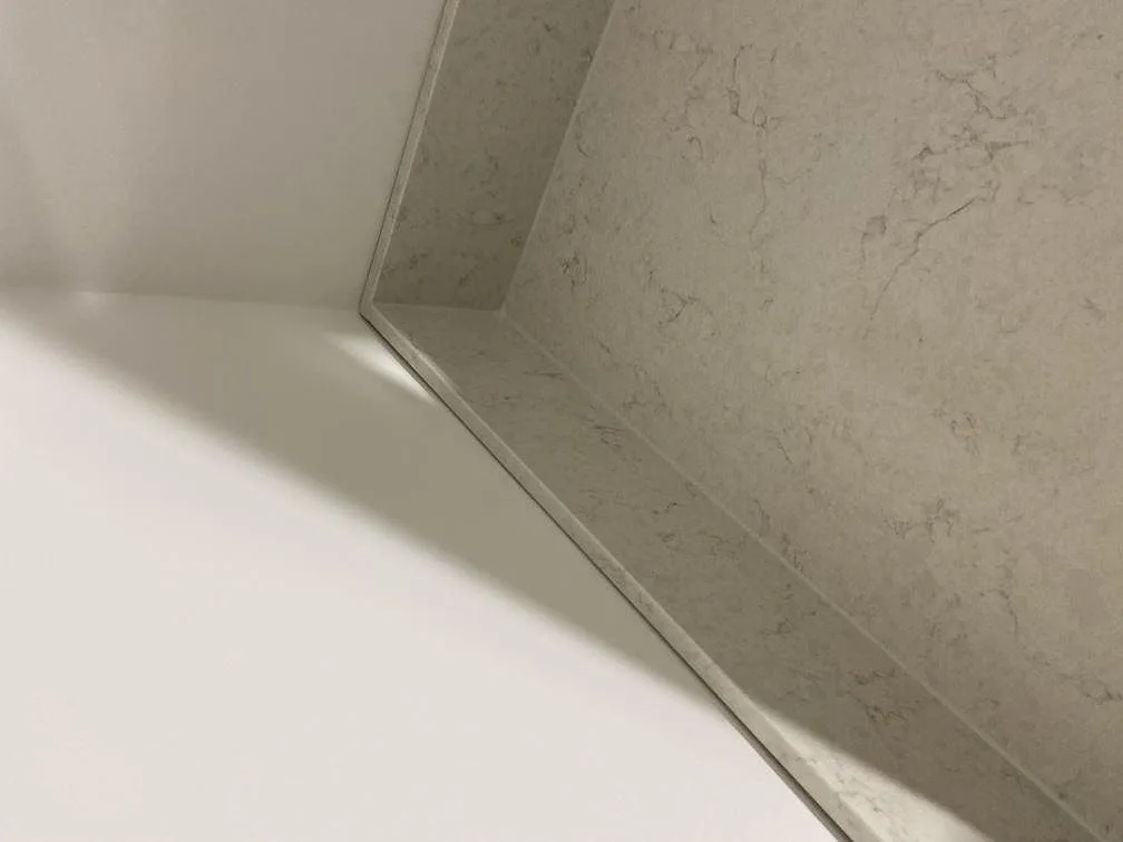 Närbild på den polerade kanten där bänkskiva och stänkskydd i vit Silestone Snowy Ibiza möts i ett kök i Göteborg.