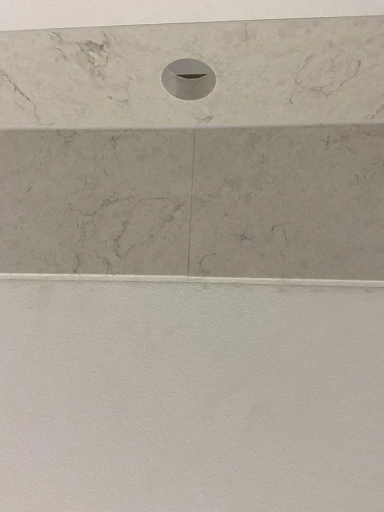 Borrat blandarehål i den polerade bänkskivan i vit Silestone Snowy Ibiza med synlig grå ådring i ett kök i Göteborg.
