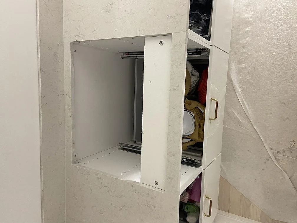 Polerad köksbänkskiva och uppvikt stänkskydd i vit Silestone Snowy Ibiza i ett kök under montering i Göteborg, med öppna köksstommar.