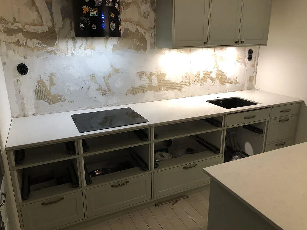 Nedsänkt mörk diskho i komposit i en polerad köksbänkskiva i vit Silestone Snowy Ibiza i ett kök i Göteborg.