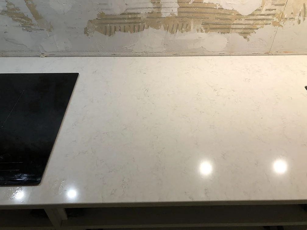 Köksö med polerad bänkskiva i vit Silestone Snowy Ibiza med mjuk grå ådring i ett kök i Göteborg.
