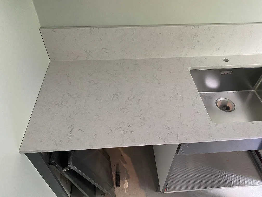 Polerad köksbänkskiva i vit Silestone Snowy Ibiza med uppvikt stänkkant och underlimmad diskho i ett kök i Göteborg.