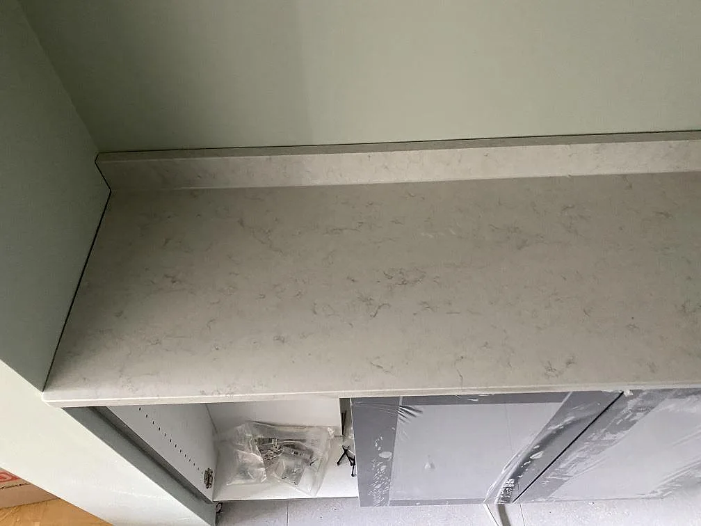 Detalj av polerad köksbänkskiva i vit Silestone Snowy Ibiza med uppvikt stänkkant i ett kök i Göteborg.