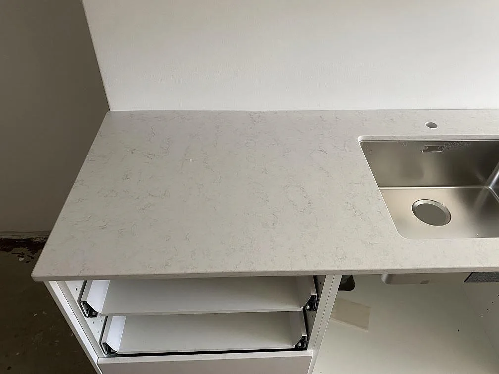 Polerad Silestone Snowy Ibiza bänkskiva med diskret grå ådring och rostfri underlimmad diskho i ett kök i Göteborg.