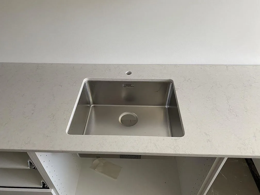 Underlimmad rostfri diskho i polerad Silestone Snowy Ibiza köksbänkskiva med mjuk grå ådring i ett kök i Göteborg.