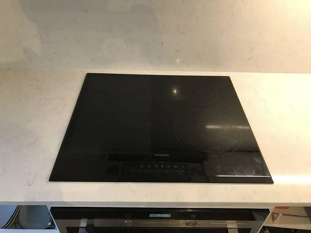 Polerad köksbänkskiva i Silestone Snowy Ibiza med infälld svart Siemens induktionshäll och ugn under, kök i Göteborg.