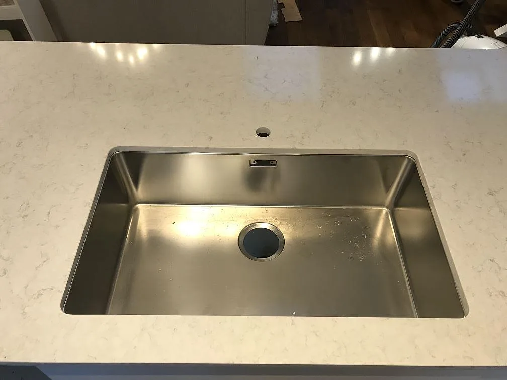 Stor underlimmad rostfri diskho i polerad Silestone Snowy Ibiza med separat borrat blandarhål i stenen, kök i Göteborg.