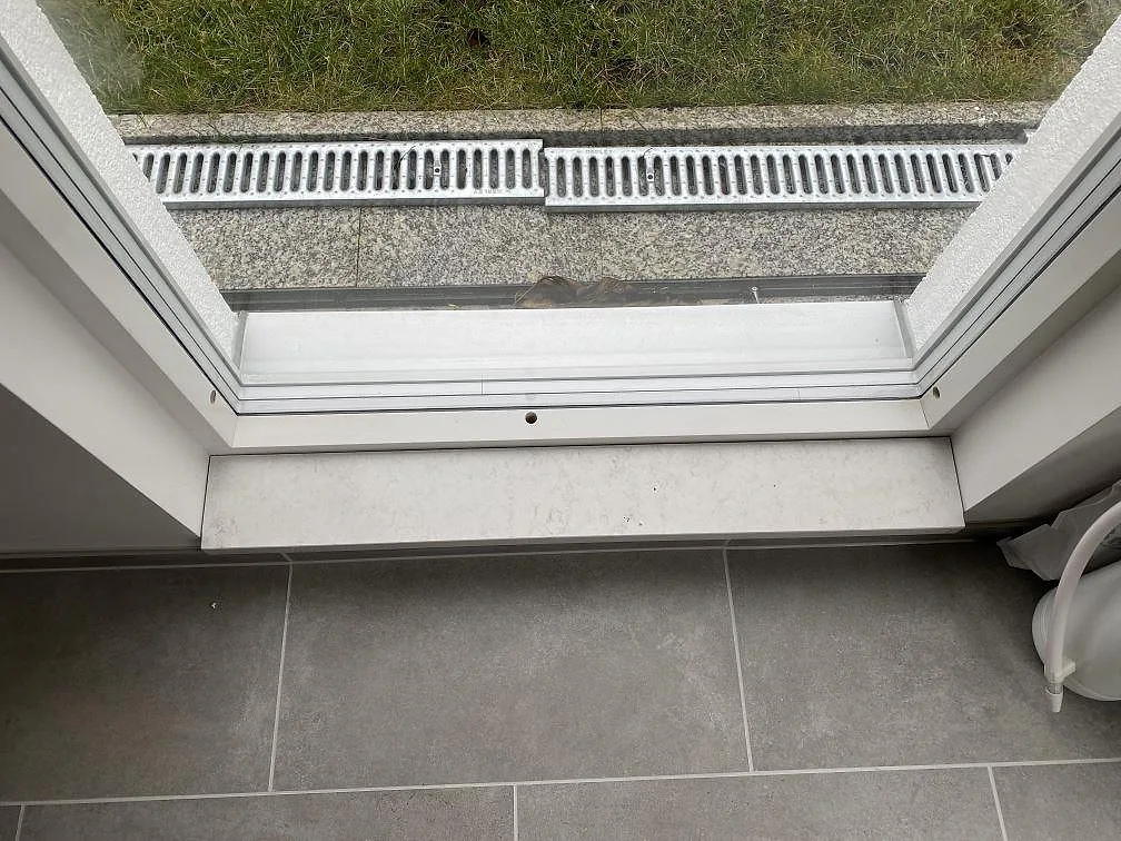 Detalj av fönsterbänkens hörn i vit Silestone Snowy Ibiza mot tilat golv och fönsterkarm i ett rum i Göteborg.