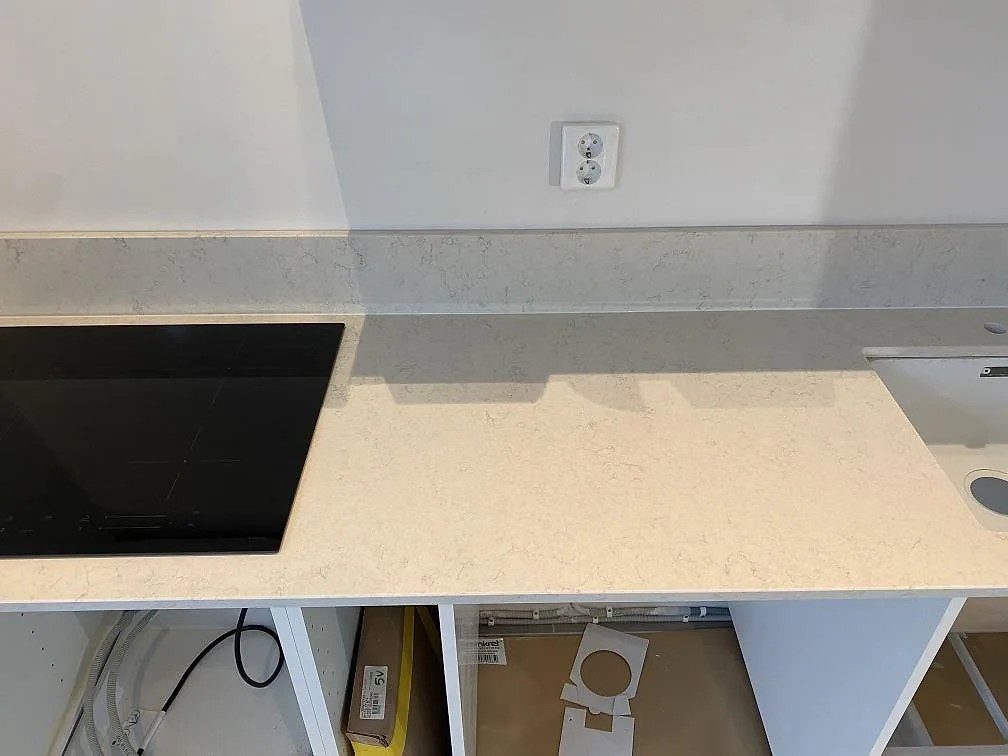 Rak köksrad i Silestone Snowy Ibiza i Göteborg med induktionshäll till vänster och utrymme för diskho till höger, fotograferad under montering.