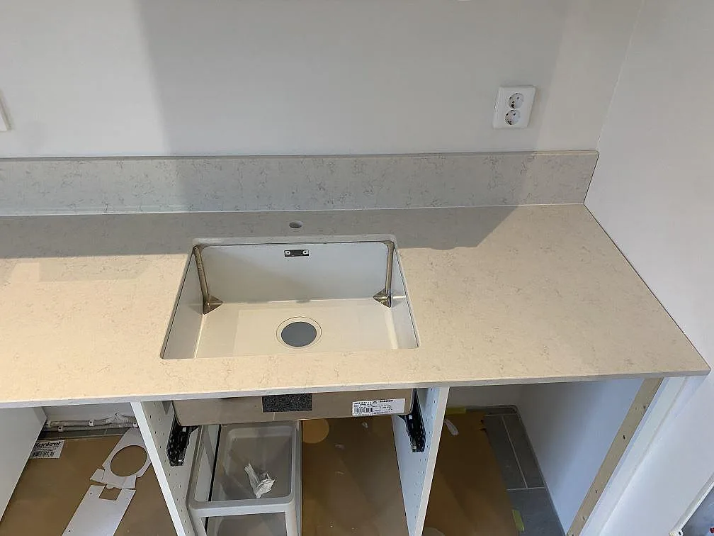 Underlimmad vit fyrkantig diskho i en polerad köksbänkskiva i Silestone Snowy Ibiza i ett kök i Göteborg.