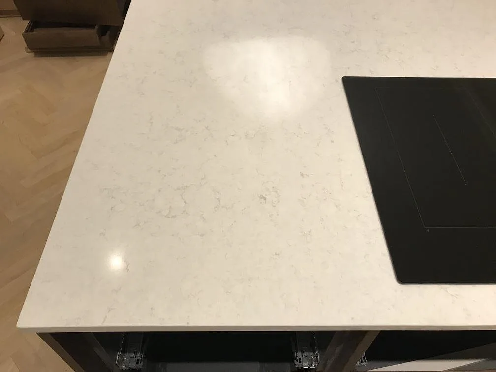 Köksö i polerad Silestone Snowy Ibiza med induktionshäll monterad ovanpå stenen i ett kök i Göteborg.