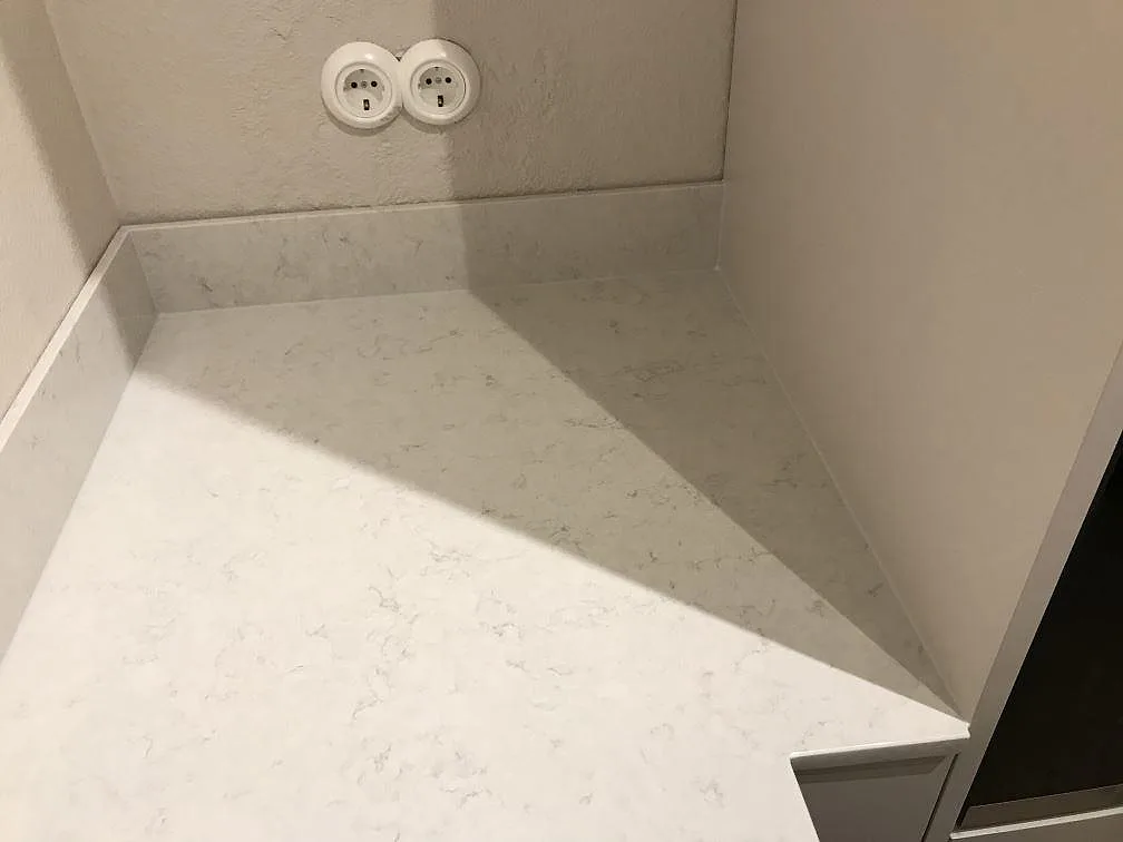 Hörnparti av köksbänk i polerad Silestone Snowy Ibiza med uppvikt stänkkant i ett kök i Göteborg.