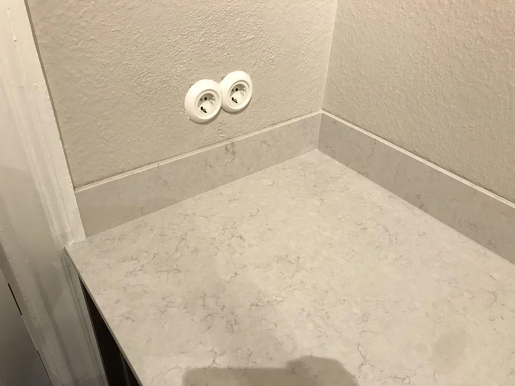 Hörnbänk i polerad Silestone Snowy Ibiza med uppvikt stänkkant mot väggarna i ett kök i Göteborg.