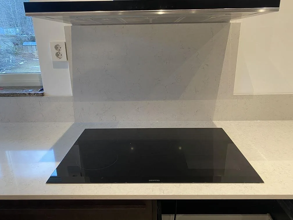 Infälld svart Siemens induktionshäll i polerad Silestone Snowy Ibiza bänkskiva med stänkskydd i samma vita kvartskomposit, Göteborg.