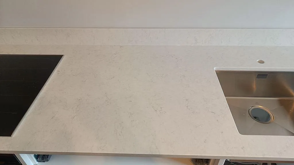 Bänkskiva i Silestone Snowy Ibiza ovanifrån med infälld induktionshäll och underlimmad rostfri diskho i ett kök i Göteborg.