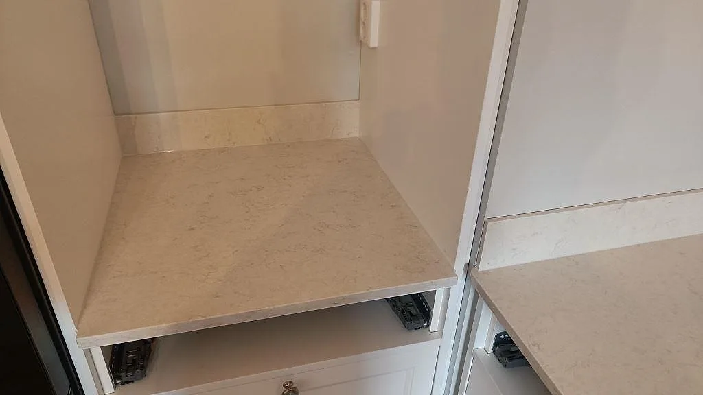 Bänkskiva i Silestone Snowy Ibiza monterad över köksstommar under montering i ett kök i Göteborg.
