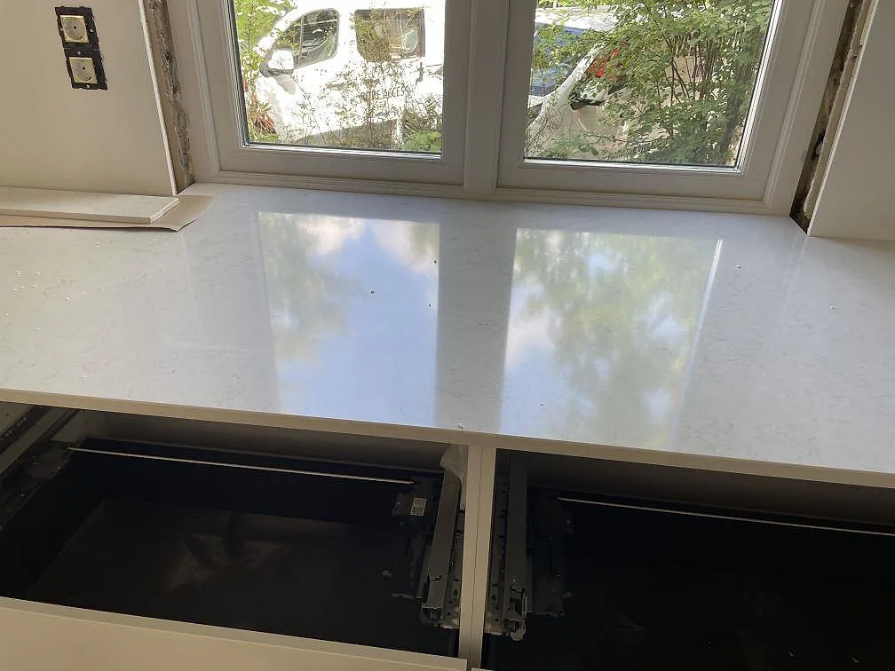 Rak bänkskivedel i vit polerad Silestone Snowy Ibiza komposit framför stora fönster i ett kök i Göteborg.