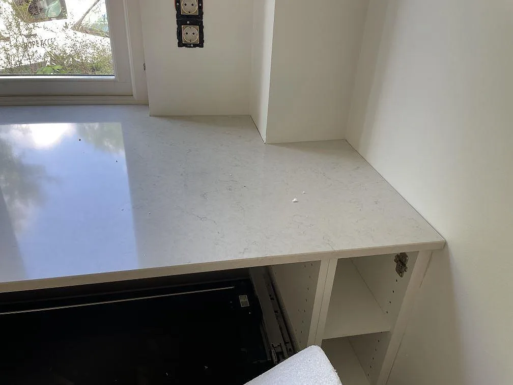 Hörndel av polerad Silestone Snowy Ibiza kompositbänkskiva vid vit köksstomme och fönster i Göteborg.