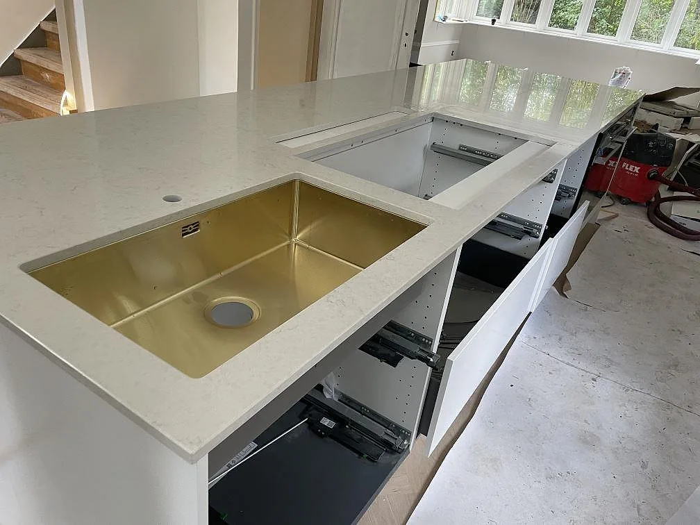 L-formad köksbänkskiva i vit polerad Silestone Snowy Ibiza komposit med mässingsfärgad underlimmad diskho i Göteborg.
