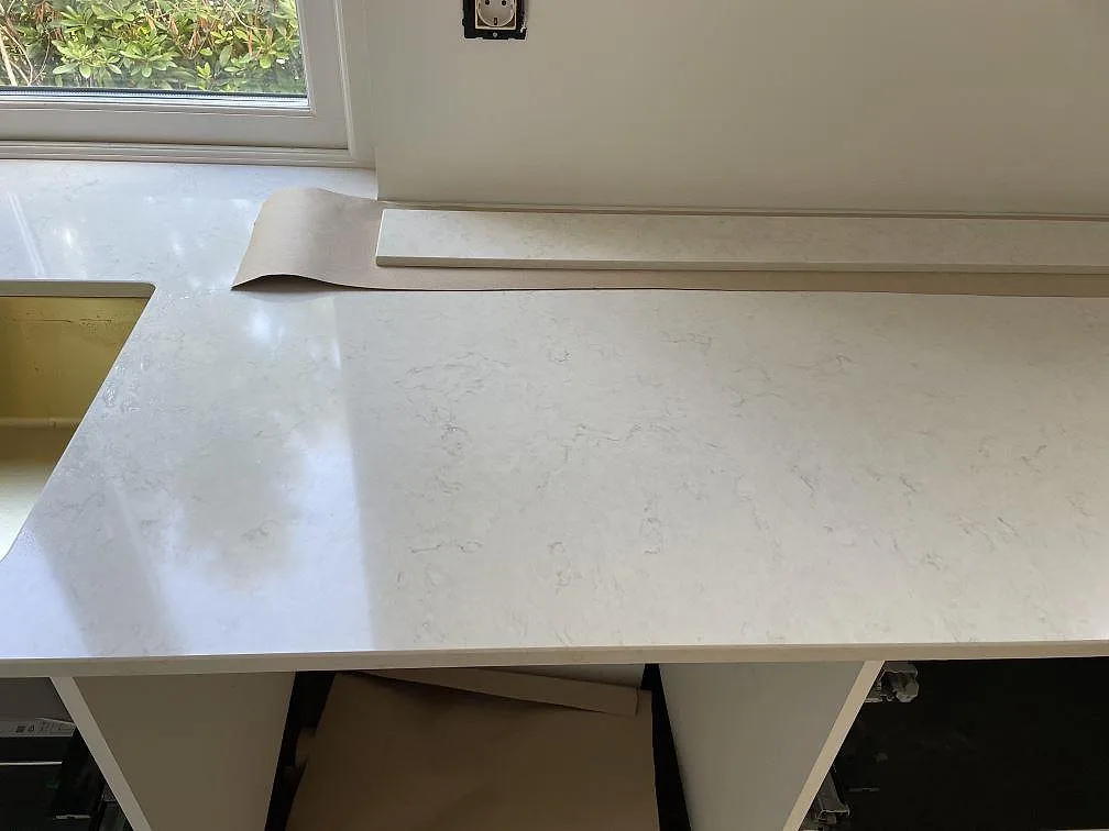 Närbild på vit polerad Silestone Snowy Ibiza bänkskiva i komposit med låg stänkkant vid fönster i Göteborg.