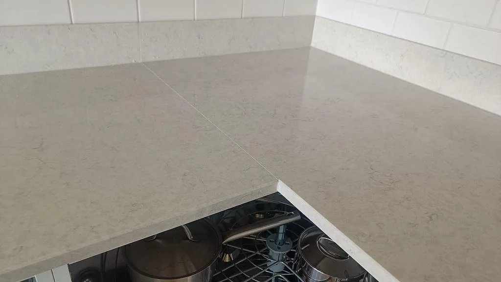 Hörn och skarv i polerad Silestone Snowy Ibiza köksbänkskiva med matchande stänkkant mot vitt kakel i Göteborg.