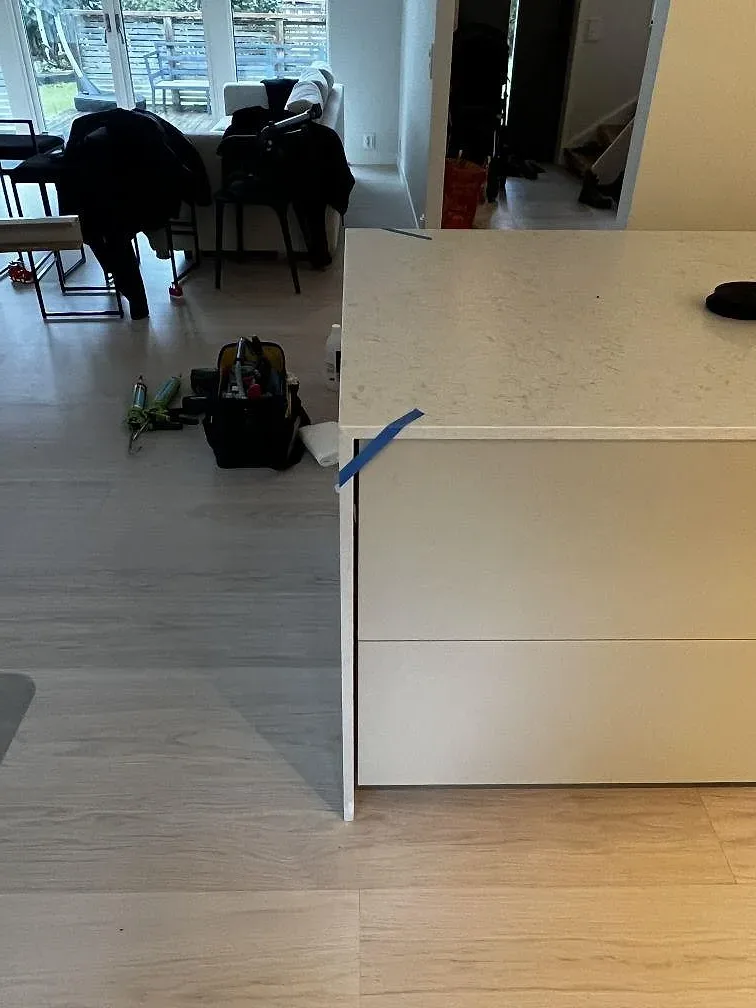 Sidovy av monterad köksbänkskiva i Silestone Snowy Ibiza komposit, Mocka, med blå tejpade skarvar i Göteborg.
