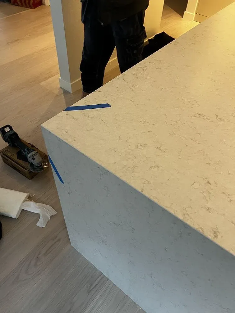 Detaljbild av monterad Silestone Snowy Ibiza komposit i Mocka på köksö med blå markeringstejp i Göteborg.