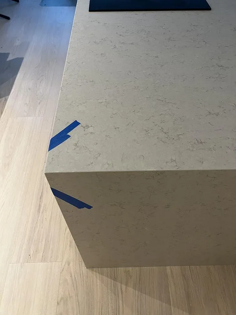 Frontvy av köksö med bänkskiva i Silestone Snowy Ibiza komposit, Mocka, och neddragen stenfront i Göteborg.