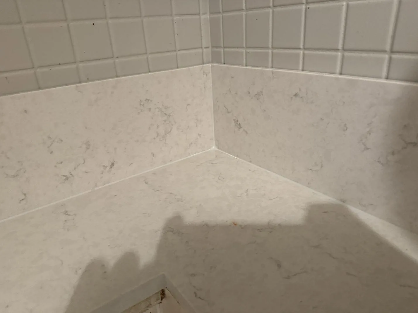 Närbild på ljus polerad Silestone Snowy Ibiza med diskret ådring, låg stänkkant och vitt kakel i Göteborg.