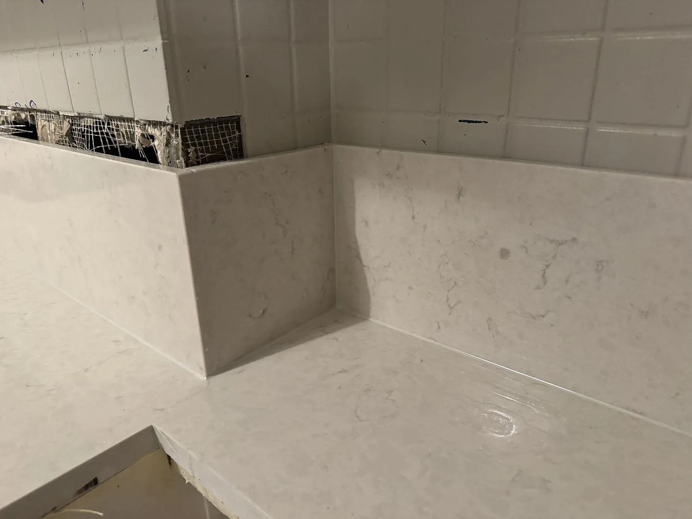 Detalj av polerad Silestone Snowy Ibiza som bänkskiva och stänkkant runt ett kökshörn under montering i Göteborg.