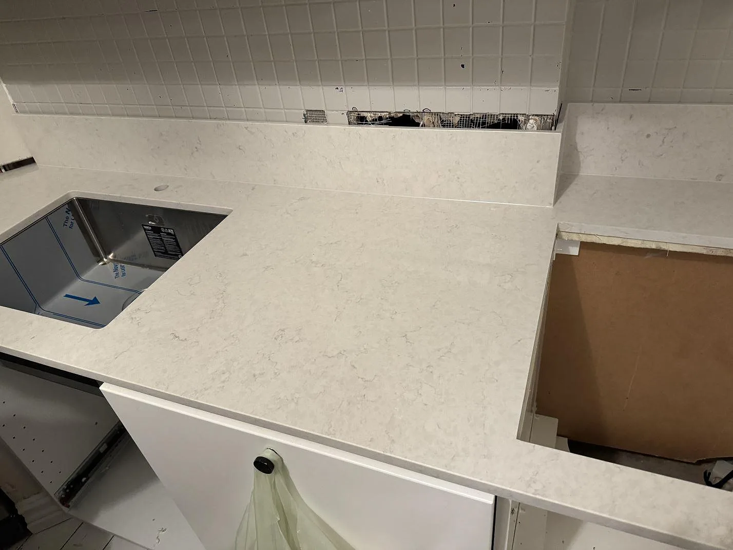Polerad Silestone Snowy Ibiza som köksbänkskiva med underlimmad rostfri diskho, rektangulärt urtag och vitt kakel i Göteborg.